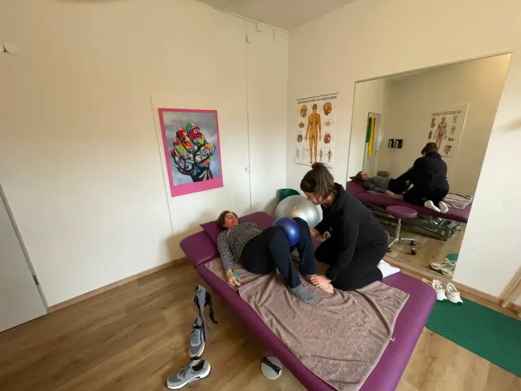 Physiotherapeutin behandelt eine liegende Patientin auf der Therapieliege